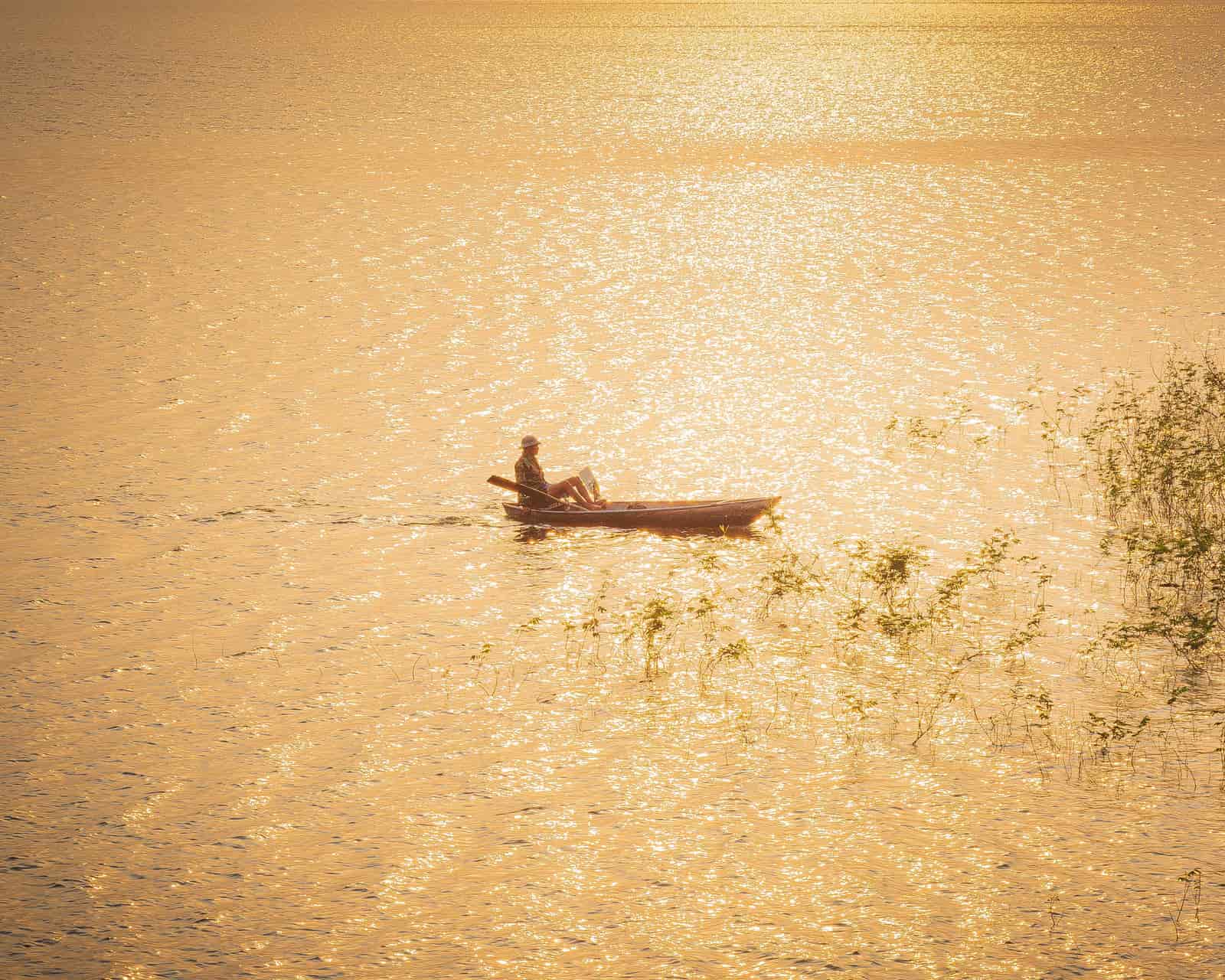 An angler on the water in bright daylight, glare across the surface
